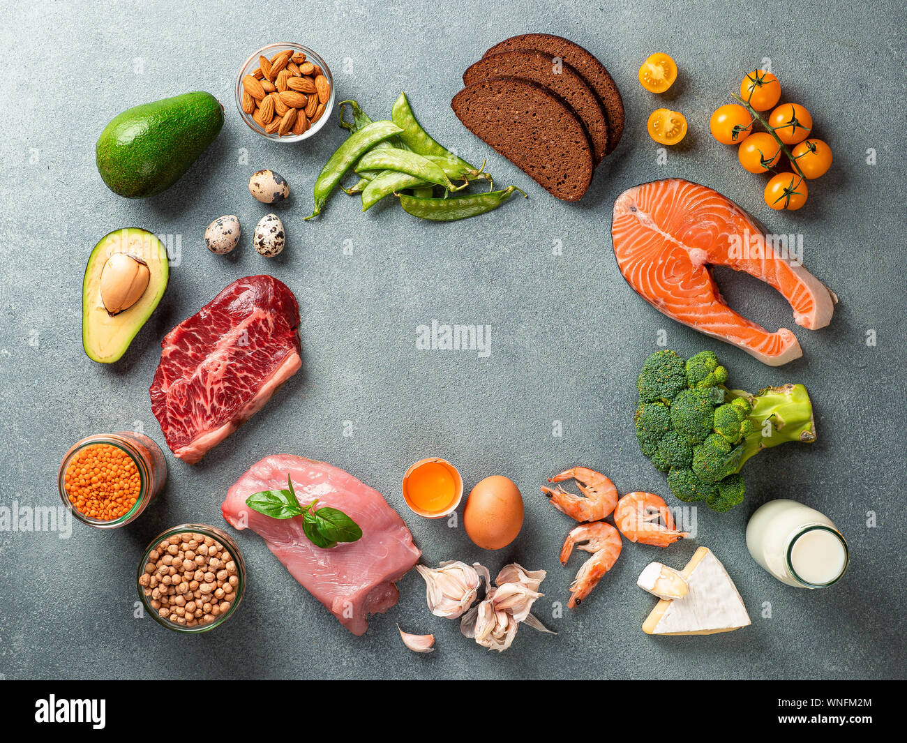 Balanced diet with copy space in center. Various healthy food ingredients on gray stone background. Top view or flat lay. Stock Photo