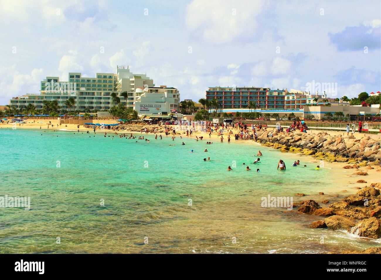 Tourists, holidaymakers & plane-spotters, relax in the sea and on the sands at Maho beach, next to Princess Juliana International Airport, St Maarten. Stock Photo
