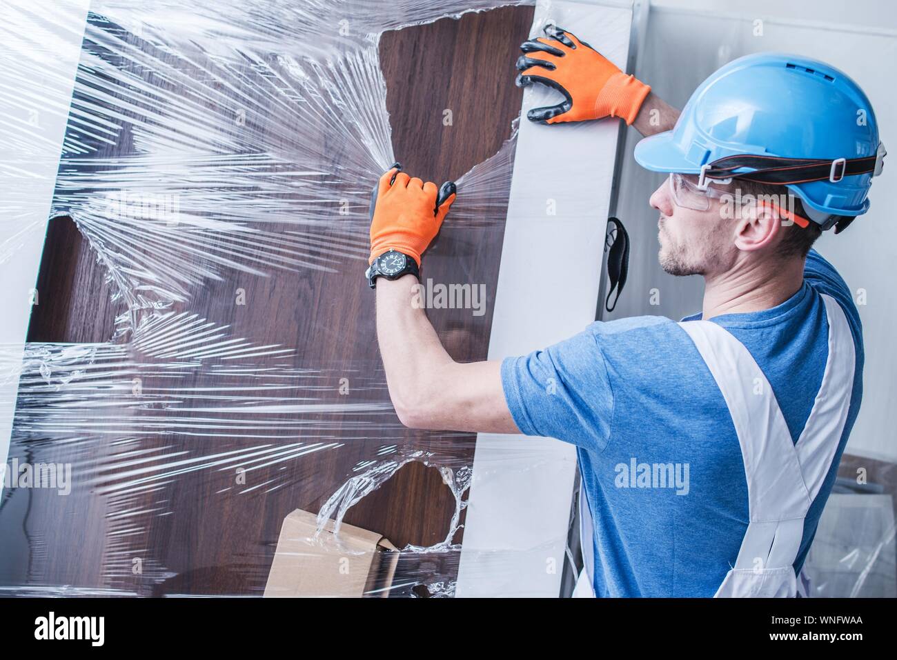 Manual Worker Removing Plastic From Door Stock Photo