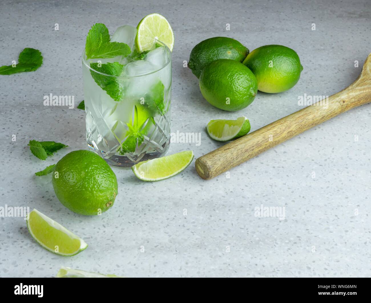 A mojito cocktail made from fresh mint and lime in a cut glass tumbler against a pale background Stock Photo