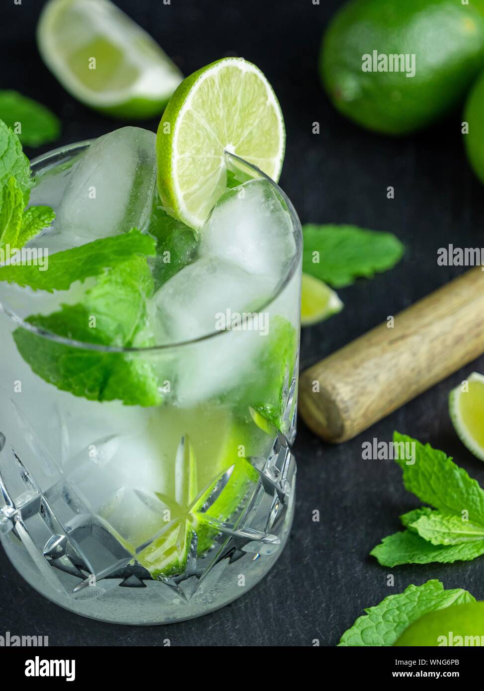 A mojito cocktail made from fresh mint and lime in a cut glass tumbler against a black slate background Stock Photo