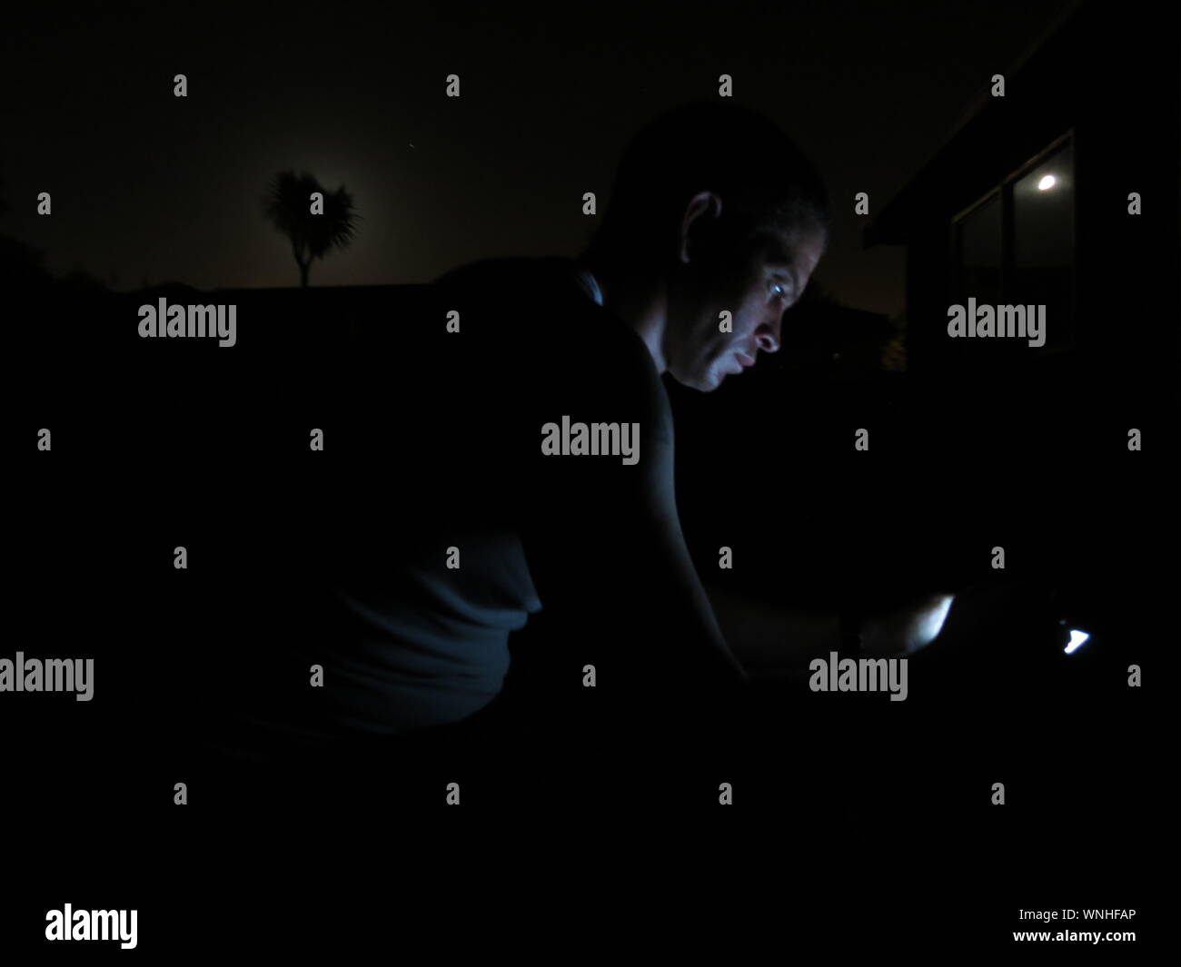 Side View Of Man By Glowing Light At Night Stock Photo
