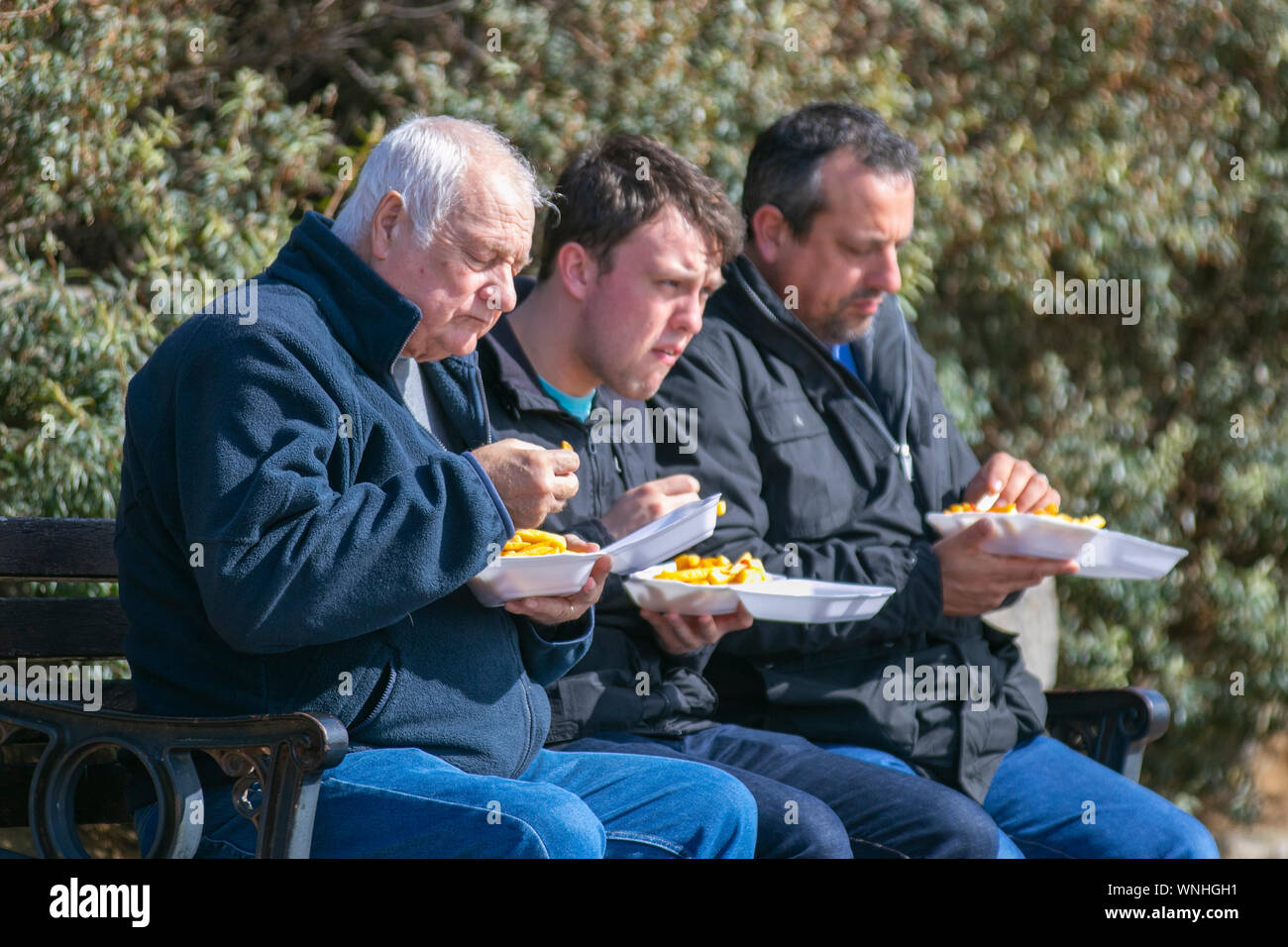 Three men eating fish and chip supper at Lytham St Annes, UK Stock Photo