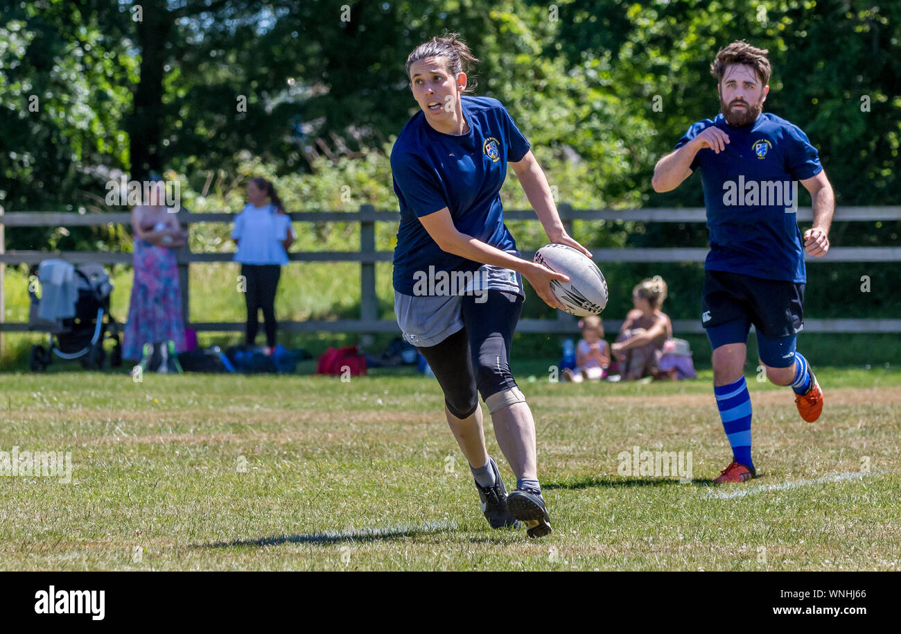 Amateur rugby touch player (female, 20-30 y) prepares to pass the ball as male teammate looks on Stock Photo