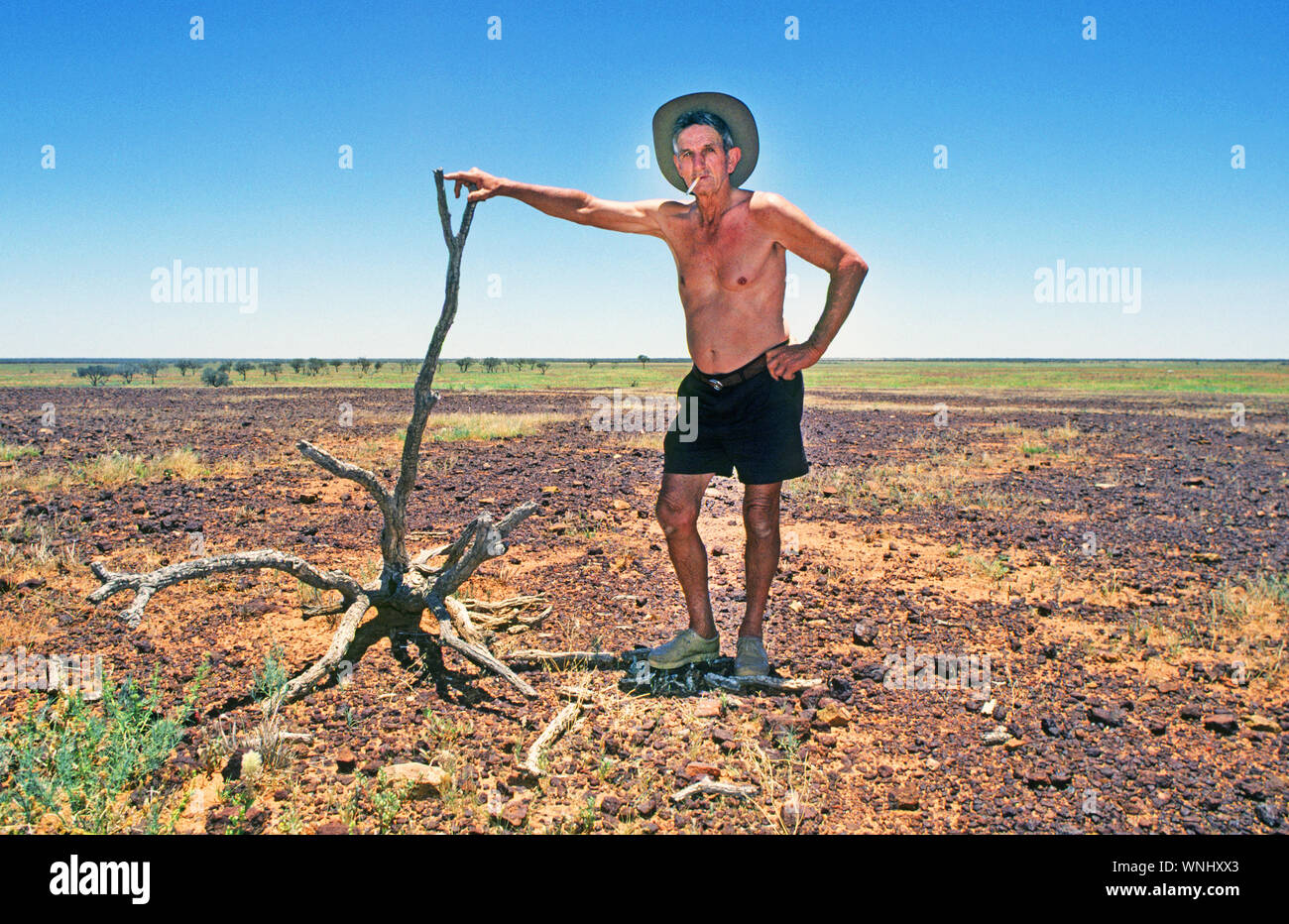 An Australian man standing in the barren desert of the Australian Outback in the Northern Territory of Australia. Stock Photo