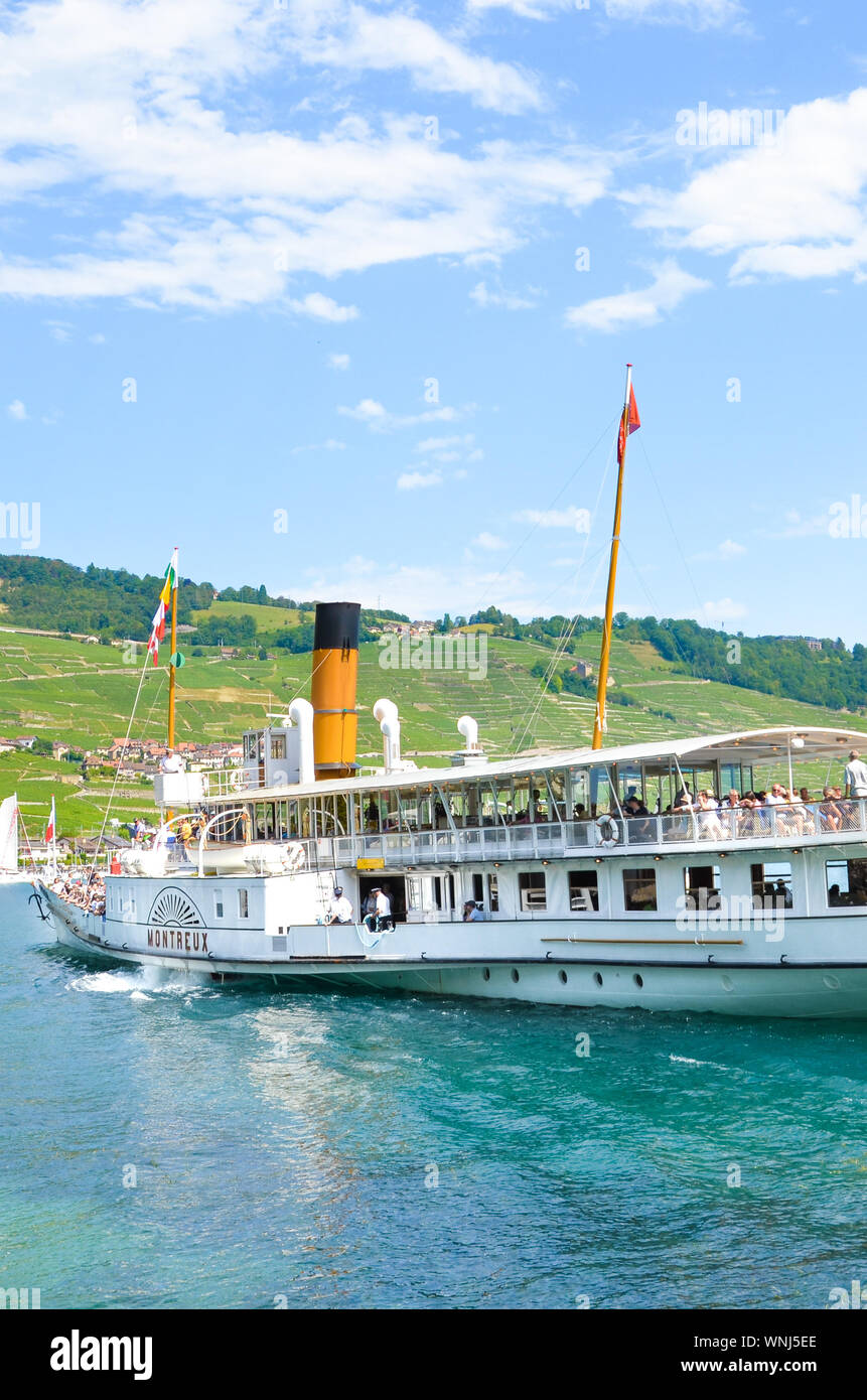 Cully, Switzerland - August 11, 2019: Sightseeing boat with tourists on Lake Geneva. Vineyards on the slopes in background. Lavaux wine region. Tourist boat, cruise. Tourism. Swiss summer. Stock Photo