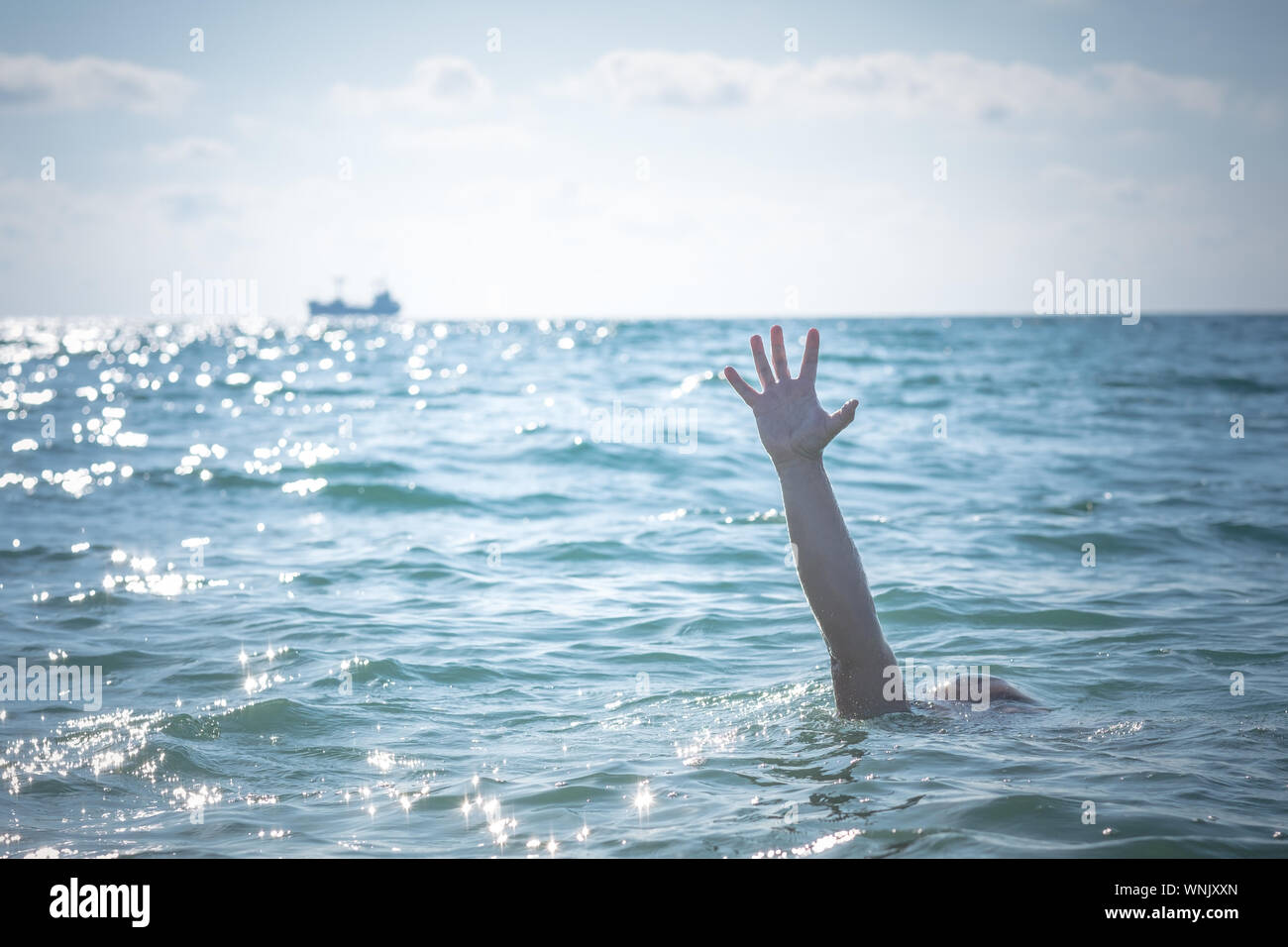 single hand of drowning man in sea asking for help. sticking out of the water Stock Photo