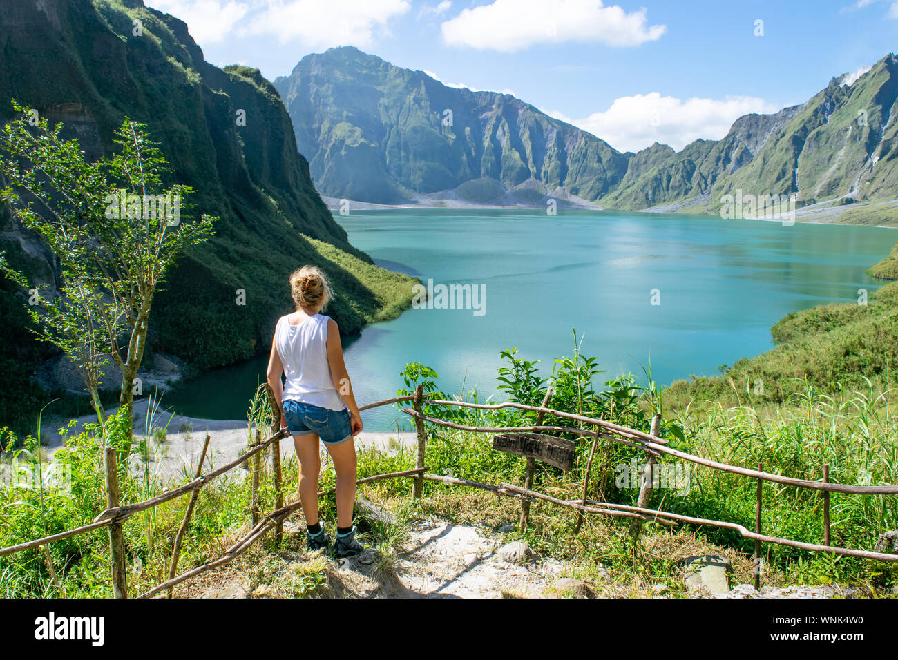 Young female tourist on ridge overlooking crater lake of Mt. Pinatubo - Luzon, Philippines Stock Photo