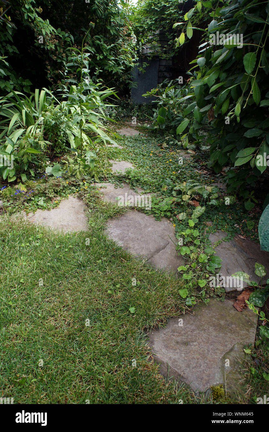 Path made of split stones laid in the garden lawn Stock Photo