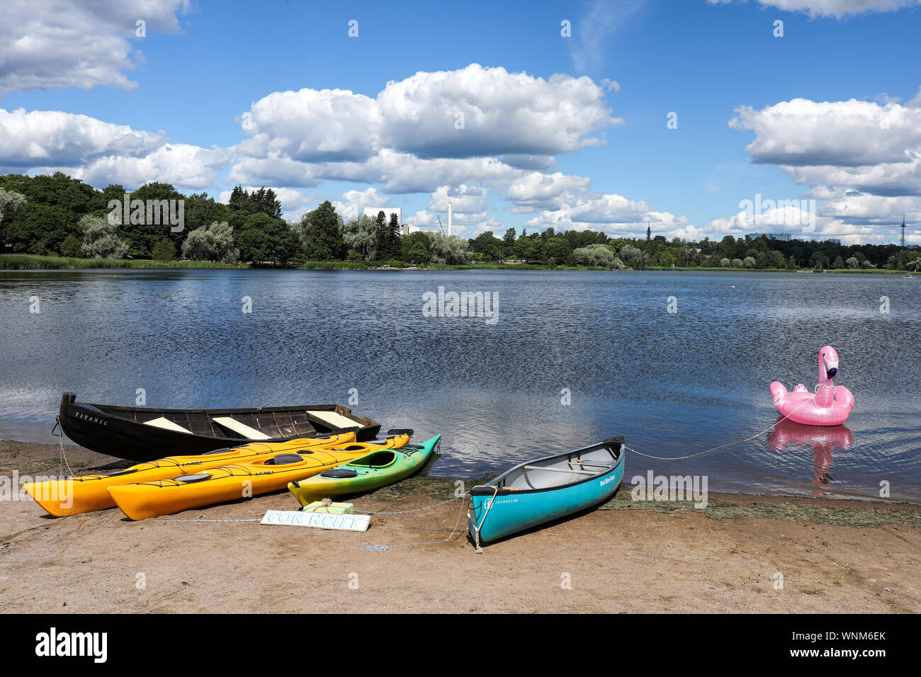 Wooden rowboat, twin kayaks and a canoe for rent at the Töölönlahti Bay in Helsinki, Finland Stock Photo