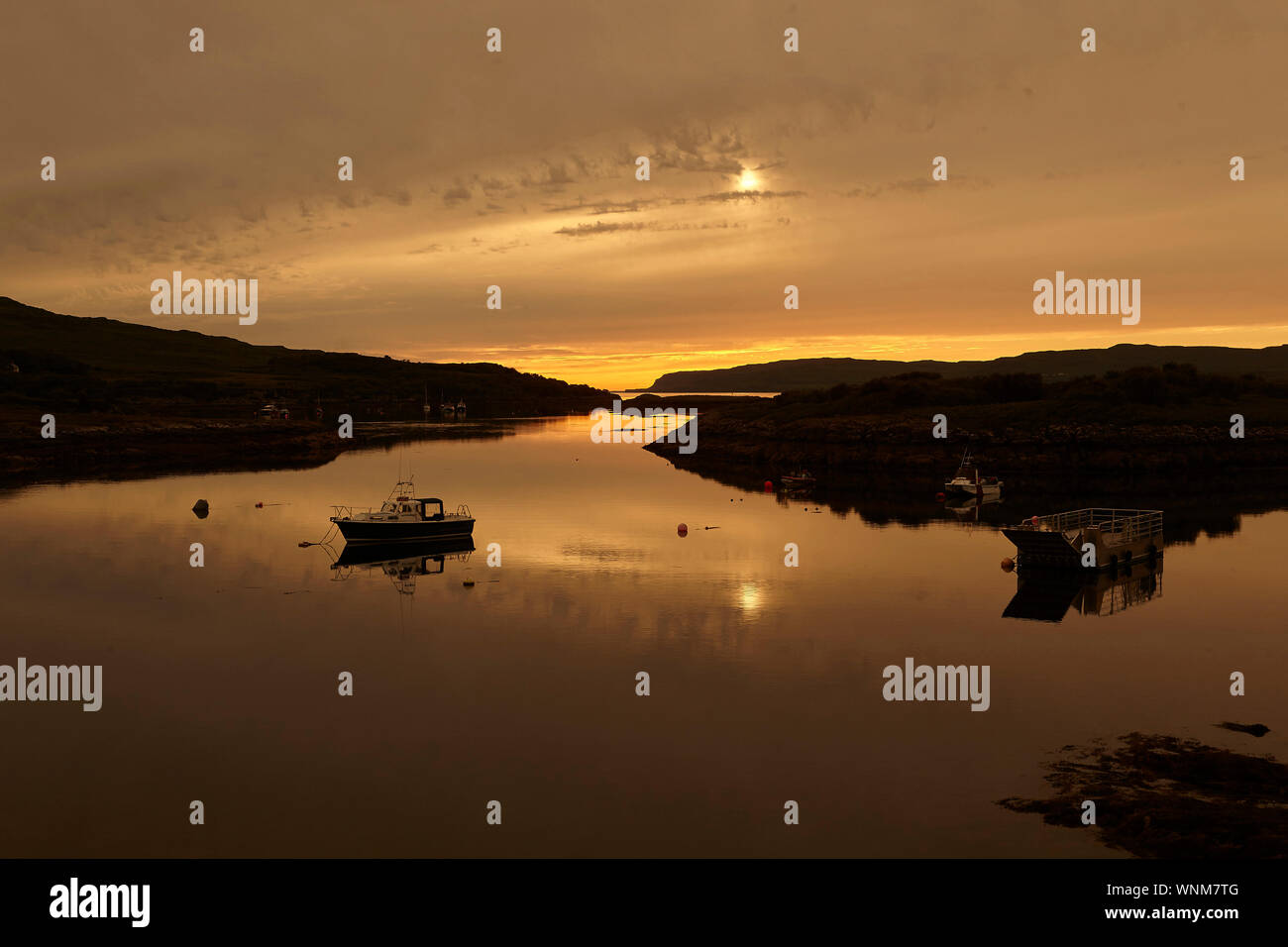 Sunset over Loch Tauth Laggan Bay, Ulva, with fishing boats and buoys, Isle of Mull, Scotland, UK. Stock Photo