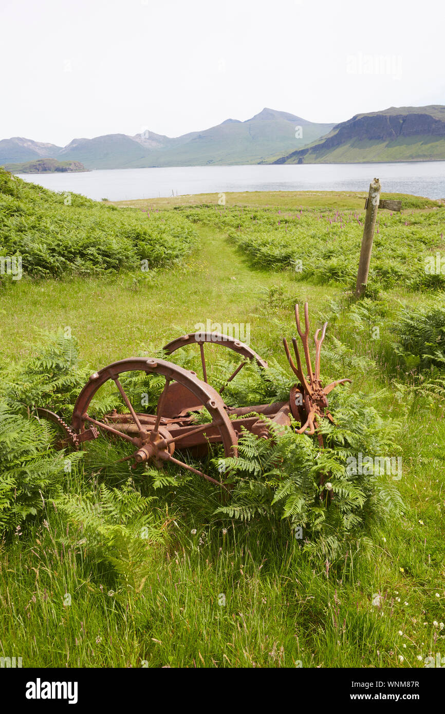 Vintage farming equipement abandoned on a raised beach on the Isle of Ulva looking to the Isle of Mull, Inner Hebrides, Scotland, UK Stock Photo