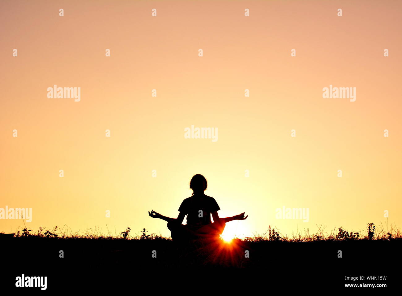Person In Lotus Position At Sunset Stock Photo
