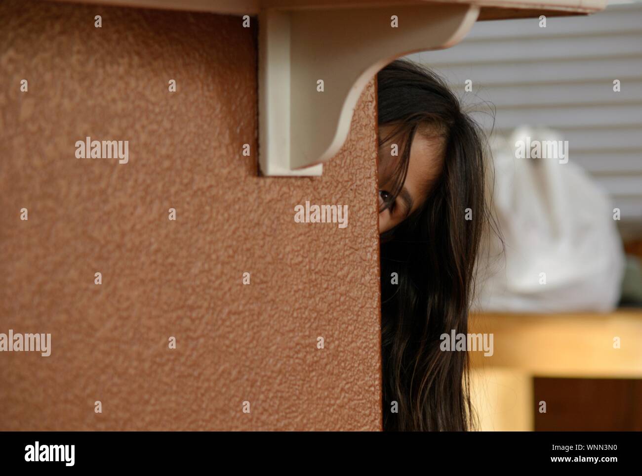 Close-up Of Girl Peaking By Wall Stock Photo