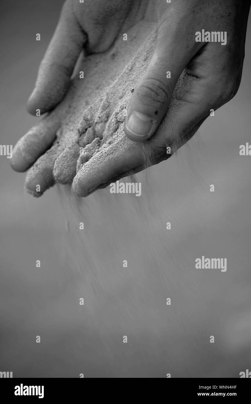 Cropped Image Of Hands With Sand Slipping Through Fingers Stock Photo