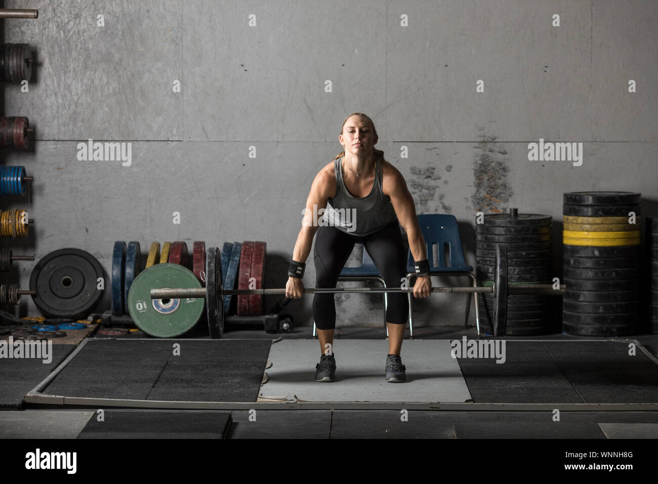 Tough young woman exercising with barbell. Determined female athlete  lifting heavy weights Stock Photo - Alamy