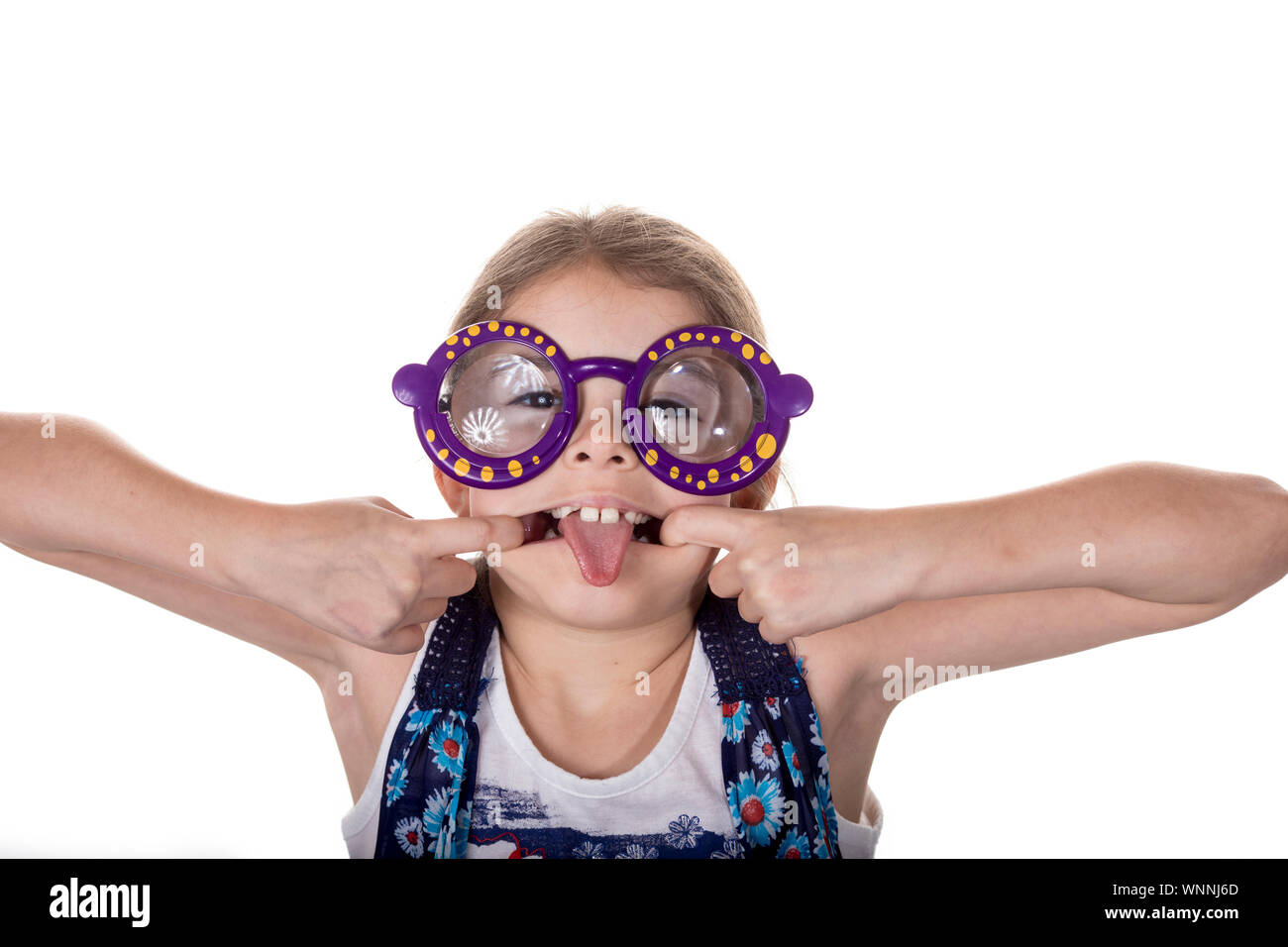 Little girl with silly glasses on making a face and sticking out tongue. Stock Photo
