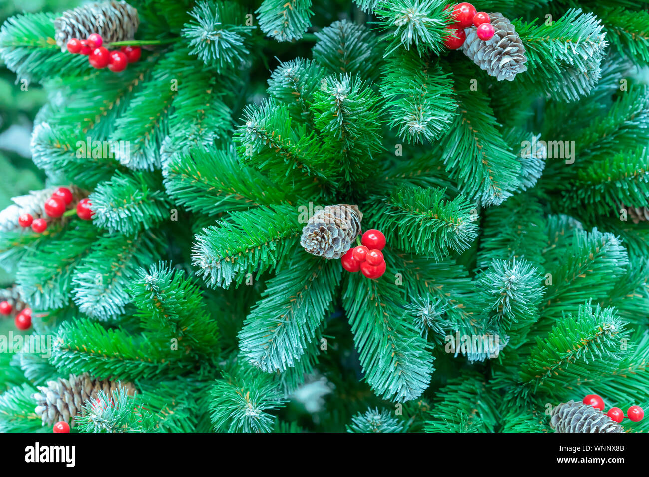 Green Christmas tree with red berries and pine cones Stock Photo Alamy