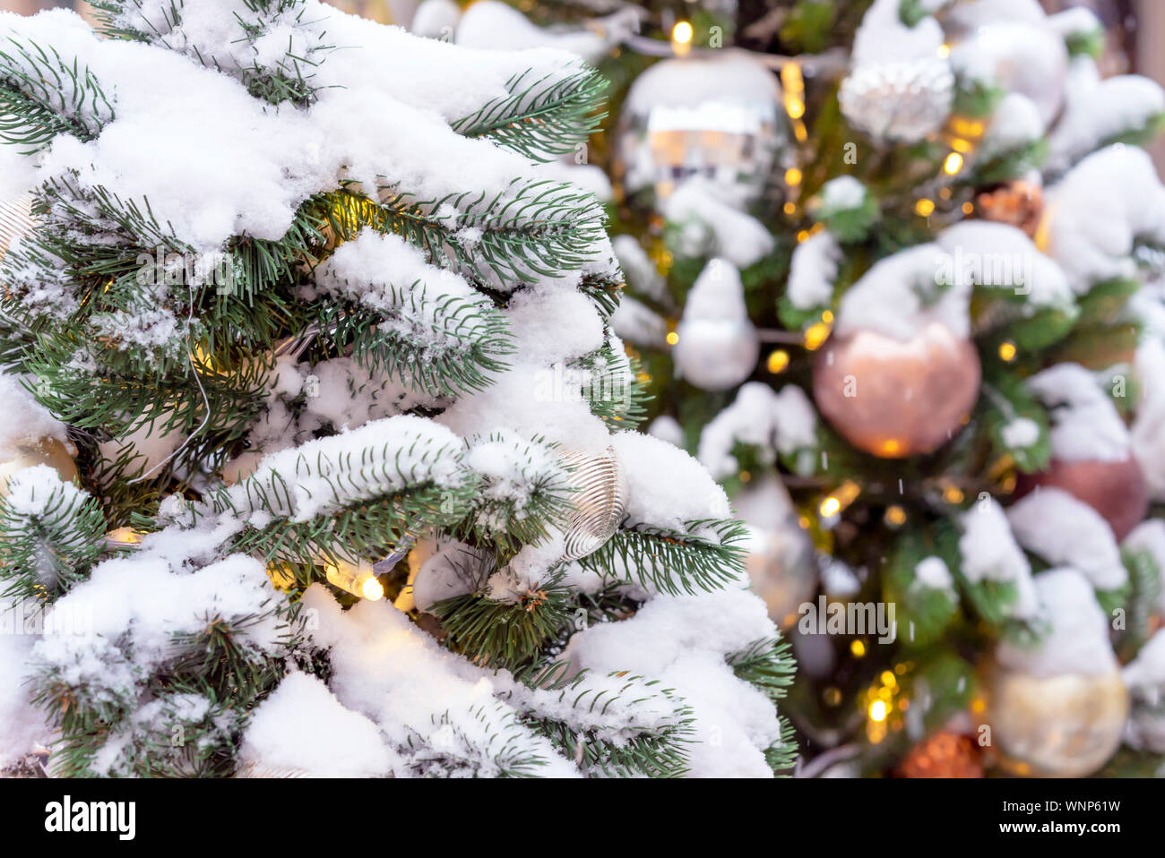 Snow-covered Christmas tree with toys and a garland Stock Photo - Alamy