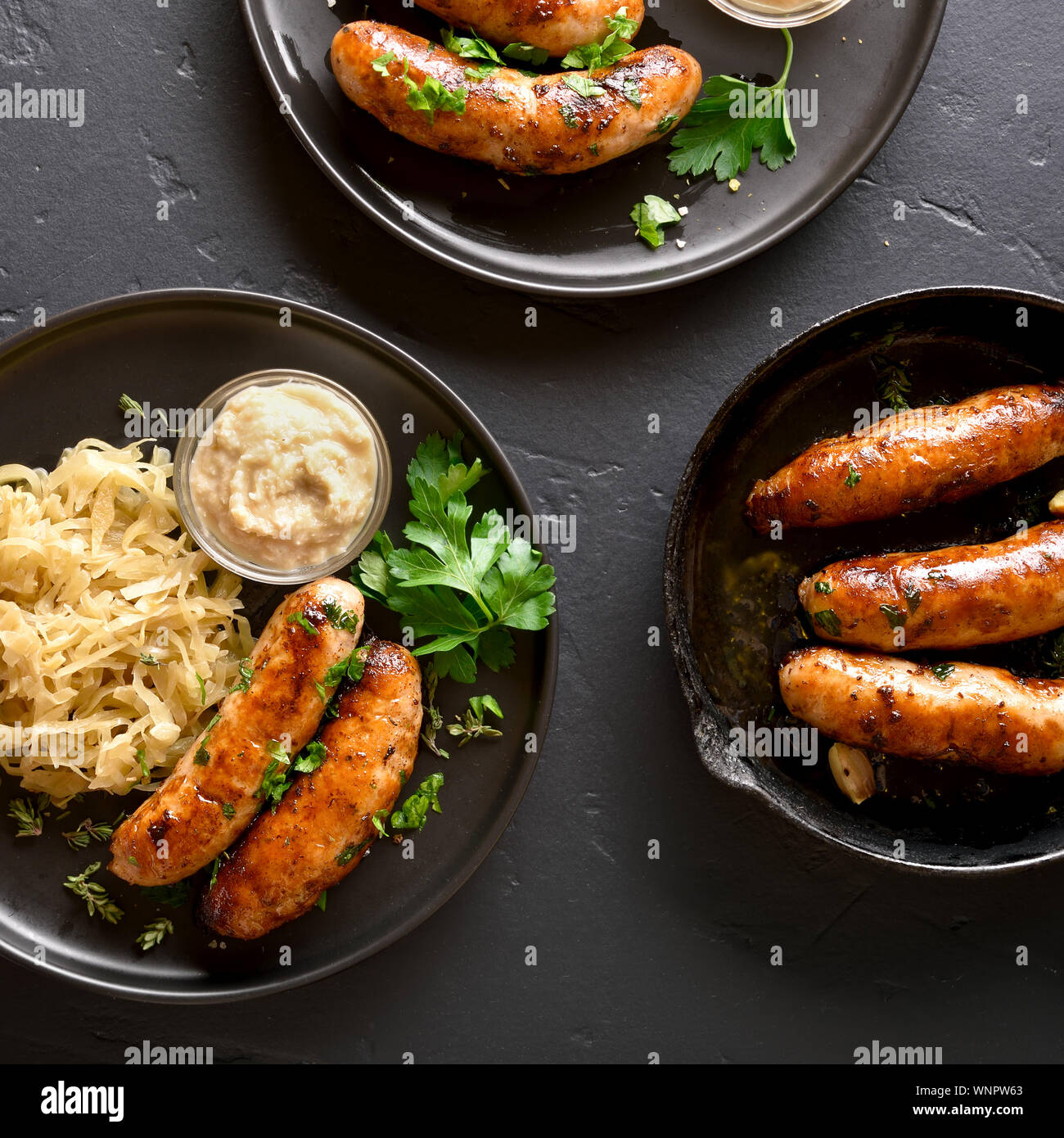 Grilled sausages with stewed sauerkraut and horseradish on plate over ...