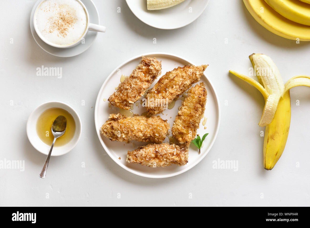 Deep fried bananas on plate over white stone background. Tasty dessert from pan fried bananas in