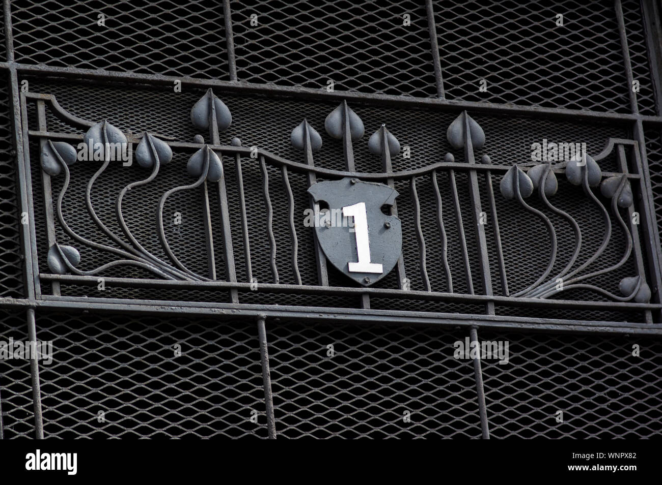 Black iron railing and grid with the number 1 on it and metal flower designs Stock Photo