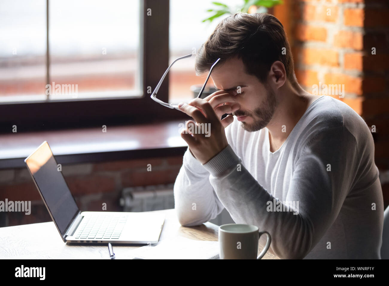 Upset man massaging nose bridge, taking off glasses, feeling eye strain
