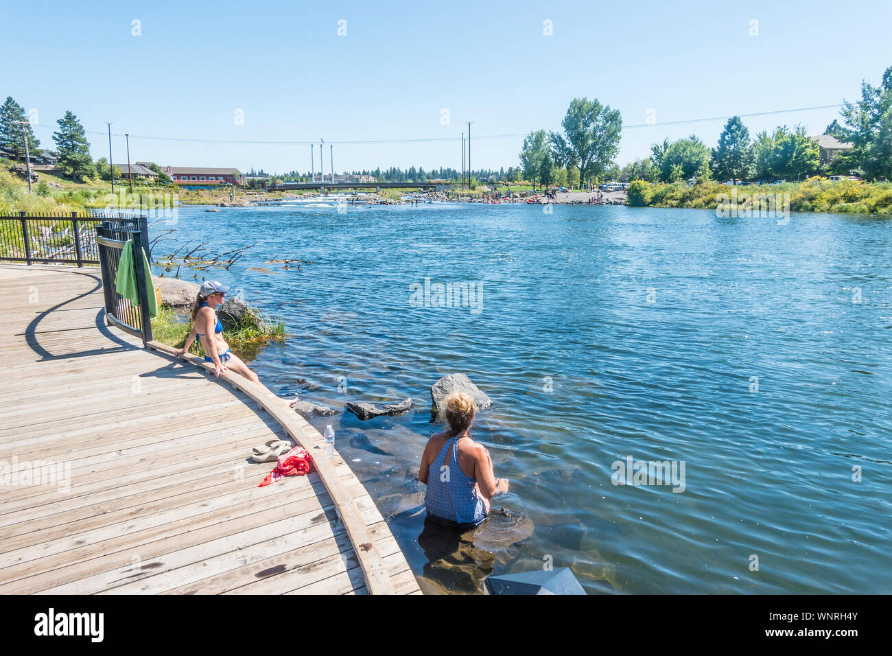 Two female sunbathers relax by the Deschutes River in Bend, Oregon. Stock Photo