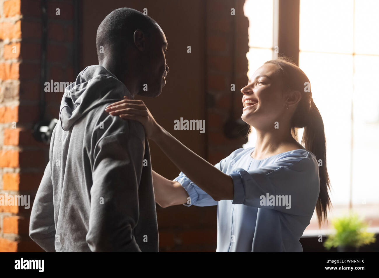 Smiling woman greeting African American man at sudden meeting Stock Photo