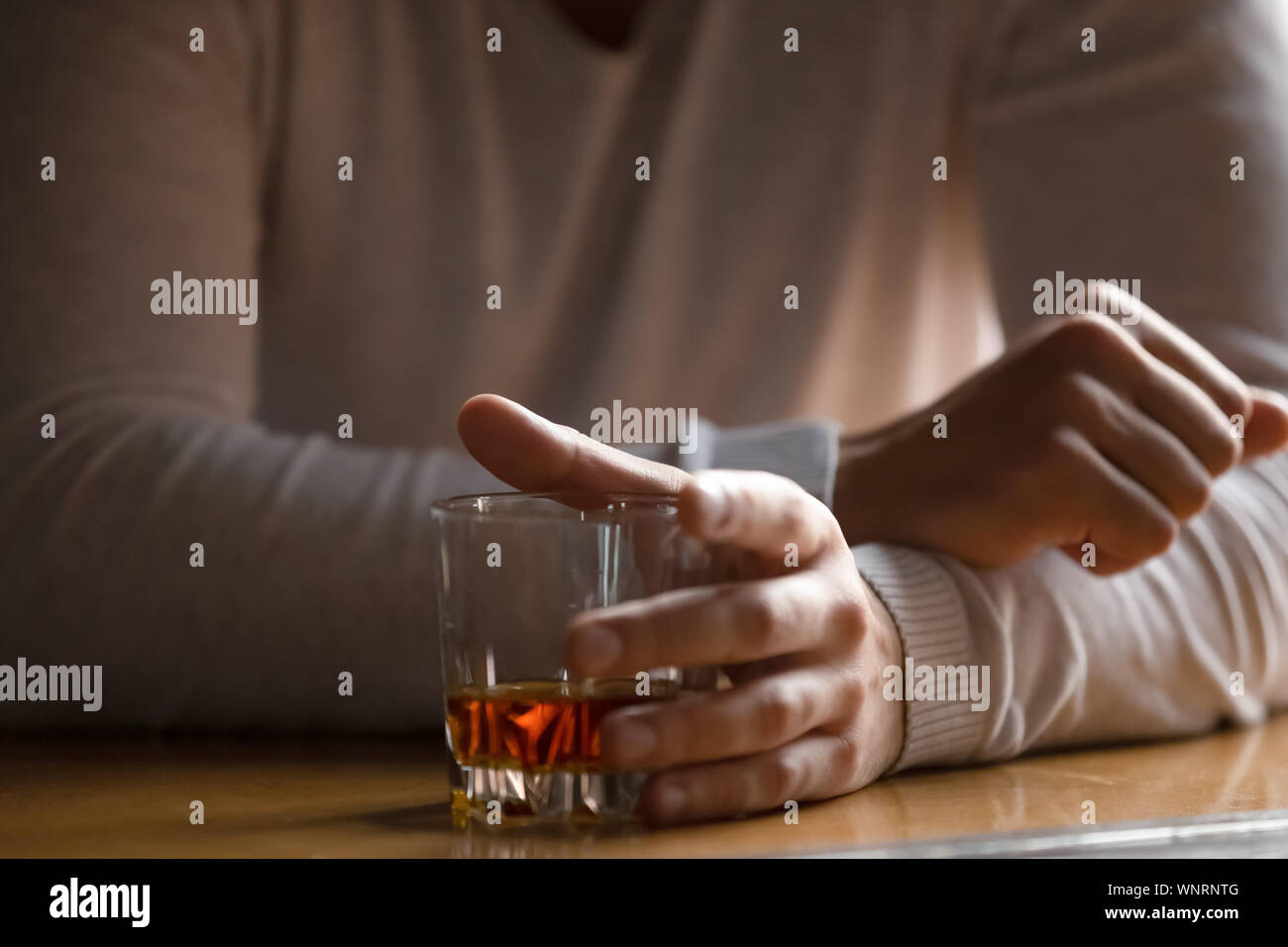 Close up man holding glass with alcohol in hand, drinking alone Stock Photo
