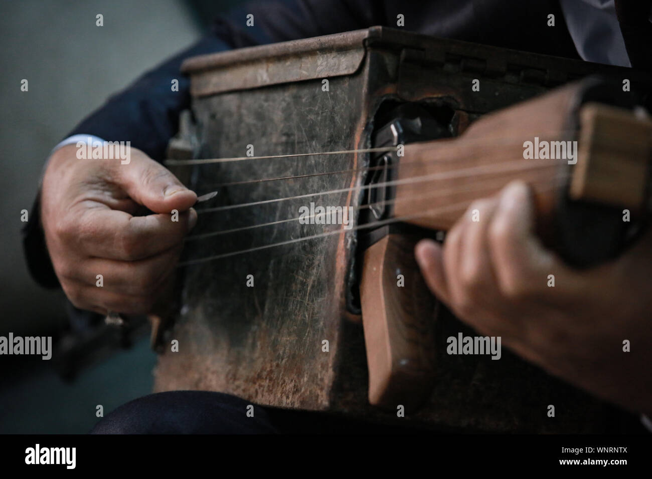 Baghdad, Iraq. 06th Sep, 2019. Iraqi teacher and musician Majed Abdennour plays a musical instrument made from a Kalashnikov assault rifle and an ammunition box. Abdennour had the Kalashnikov at home between 2006 and 2008 to protect his family during the sectarian violence between the militias and extremists of the Iraqi Sunnis and Shiites factions. After more than 10 years of abandoning his weapon, Abdennour decided to bring it to a metalworker to transform it into a musical instrument that performs as a lute. Credit: Ameer Al Mohammedaw/dpa/Alamy Live News Stock Photo