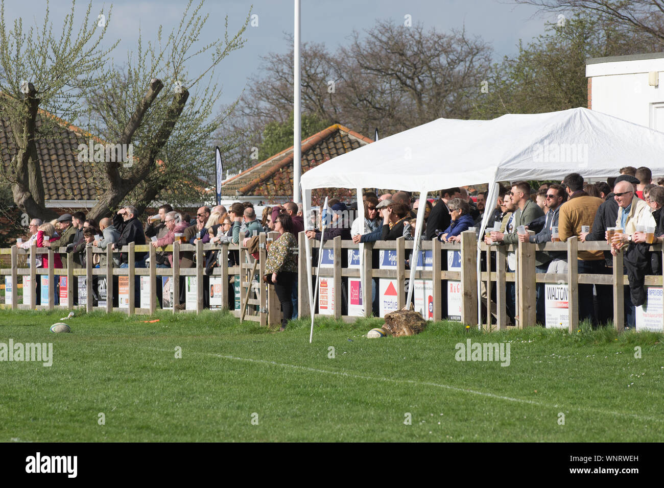 Amateur rugby club supporters pack the fence to watch local derby match Stock Photo
