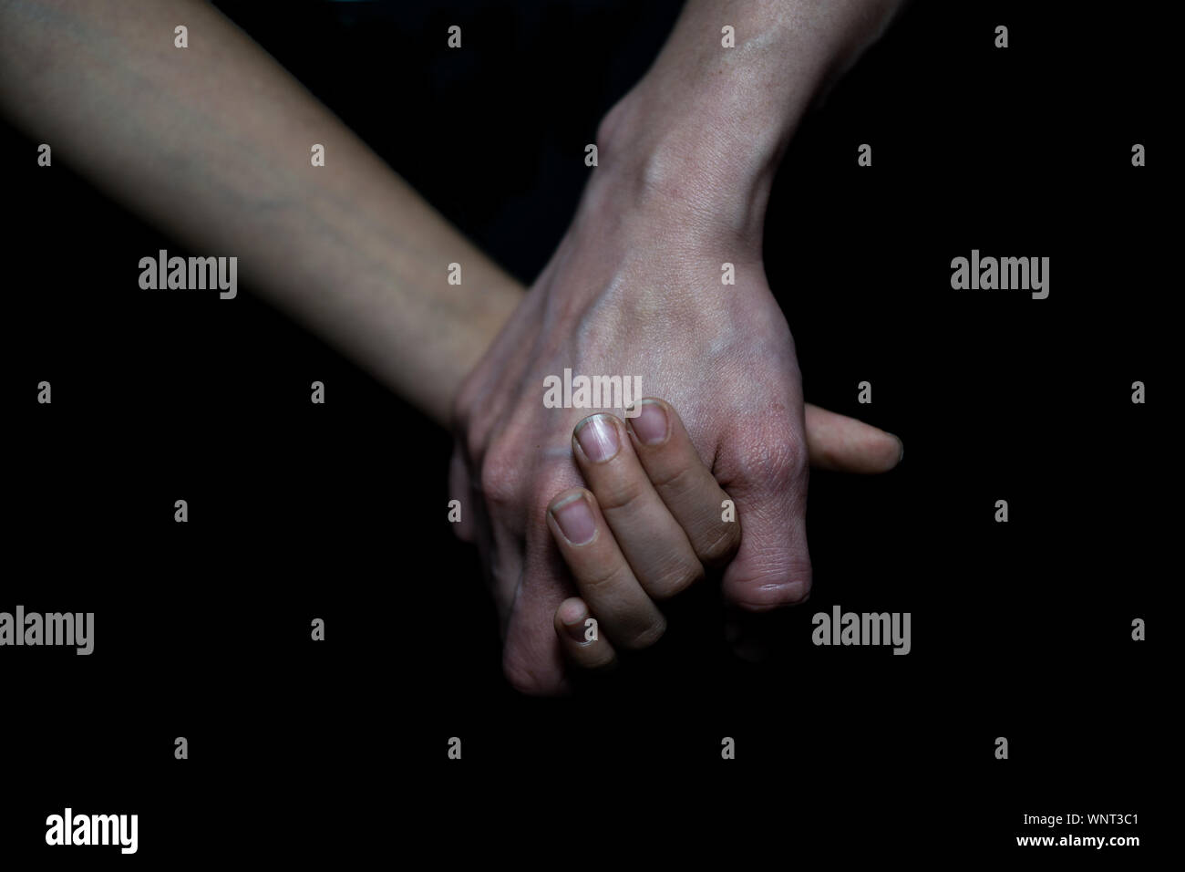 hold hands daughter and mother on black background Stock Photo - Alamy