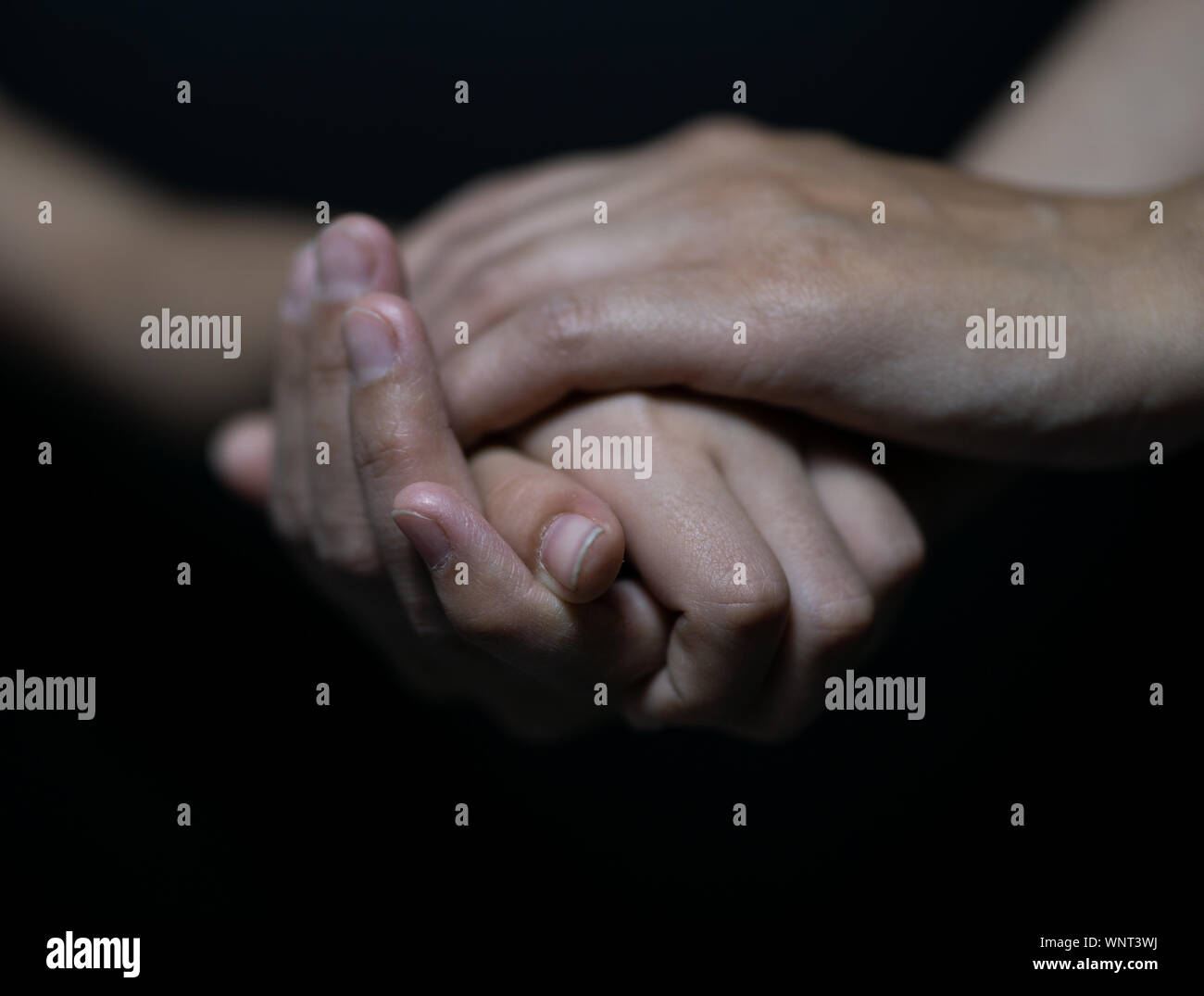 hold hands daughter and mother on black background Stock Photo - Alamy
