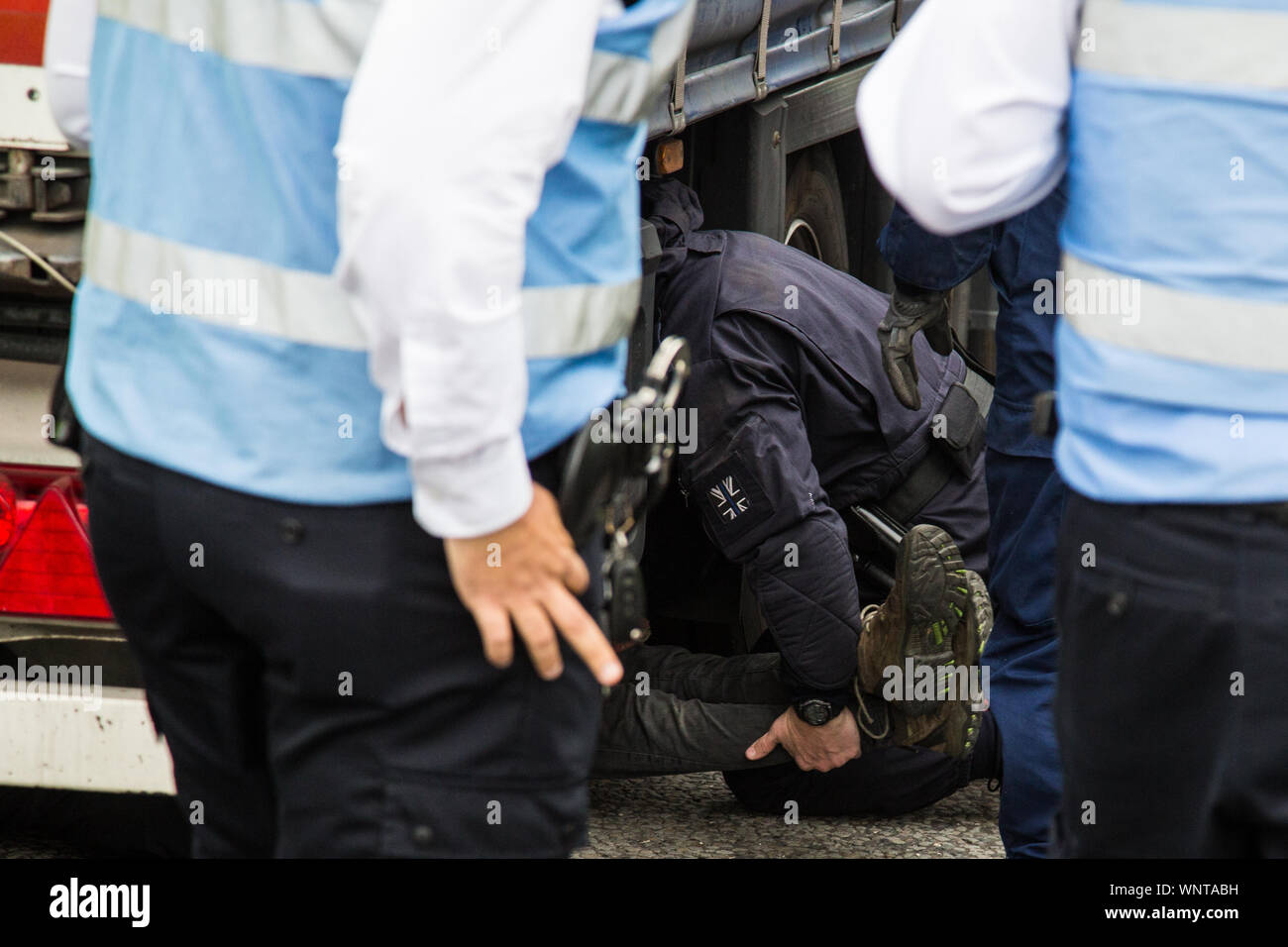 London, UK. 6 September, 2019. Metropolitan Police officers remove an activist who had locked herself beneath a truck making a delivery to ExCel London for DSEI, the world’s largest arms fair. The road remained blocked for several hours. The fifth day of protests against the arms fair was themed as Stop The Arms Fair: Stop Climate Change in order to highlight links between the fossil fuel and arms industries. Credit: Mark Kerrison/Alamy Live News Stock Photo