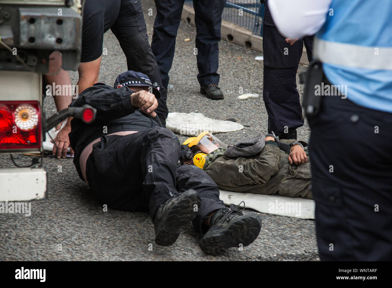 London, UK. 6 September, 2019. Metropolitan Police officers arrest an activist who had locked herself beneath a truck making a delivery to ExCel London for DSEI, the world’s largest arms fair. The road remained blocked for several hours. The fifth day of protests against the arms fair was themed as Stop The Arms Fair: Stop Climate Change in order to highlight links between the fossil fuel and arms industries. Credit: Mark Kerrison/Alamy Live News Stock Photo