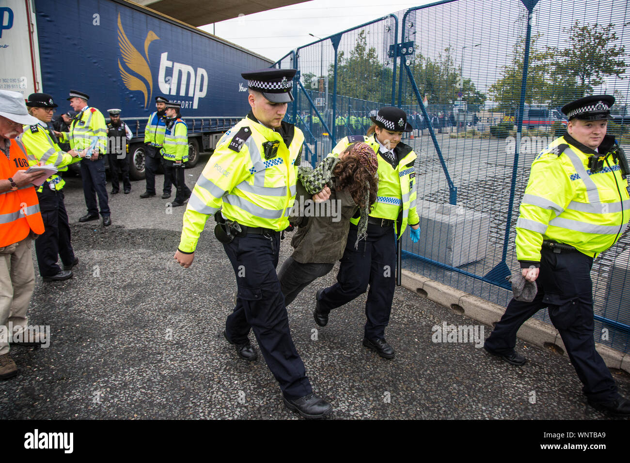 London, UK. 6 September, 2019. Metropolitan Police officers arrest an activist who had locked herself beneath a truck making a delivery to ExCel London for DSEI, the world’s largest arms fair. The road remained blocked for several hours. The fifth day of protests against the arms fair was themed as Stop The Arms Fair: Stop Climate Change in order to highlight links between the fossil fuel and arms industries. Credit: Mark Kerrison/Alamy Live News Stock Photo