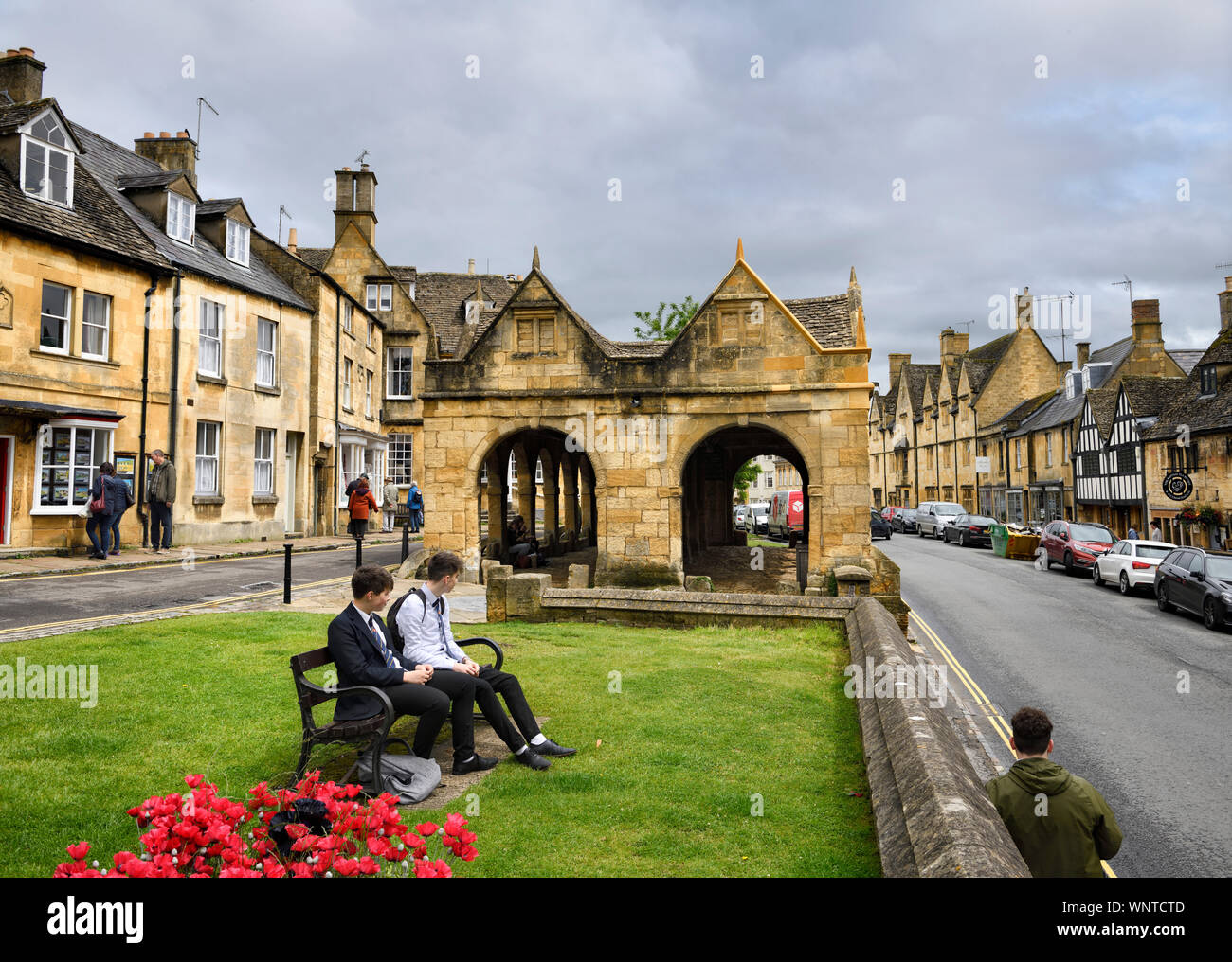 Students and tourists lunchtime at 17th Century Market Hall with Cotswold yellow stone on High street Chipping Campden England Stock Photo