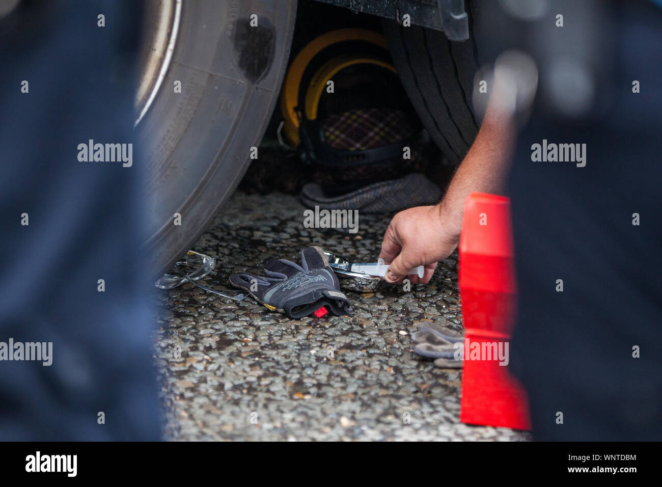 London, UK. 6 September, 2019. Metropolitan Police officers work to remove an activist locked beneath a truck making a delivery to ExCel London for DSEI, the world’s largest arms fair. The road remained blocked for several hours. The fifth day of protests against the arms fair was themed as Stop The Arms Fair: Stop Climate Change in order to highlight links between the fossil fuel and arms industries. Credit: Mark Kerrison/Alamy Live News Stock Photo