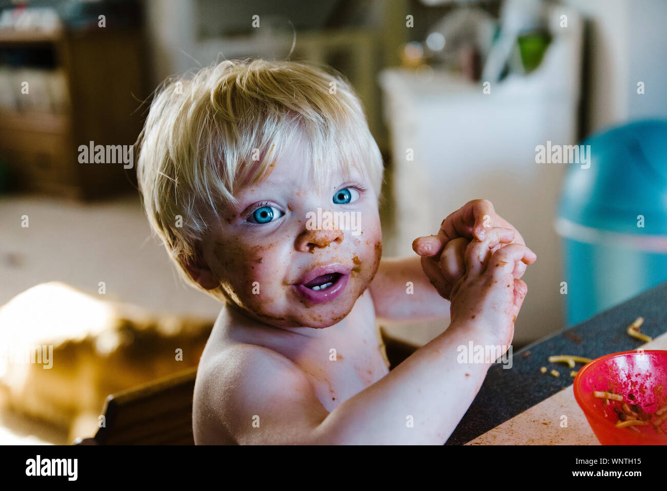 One year old little boy sitting at table with spaghetti all over face. Stock Photo