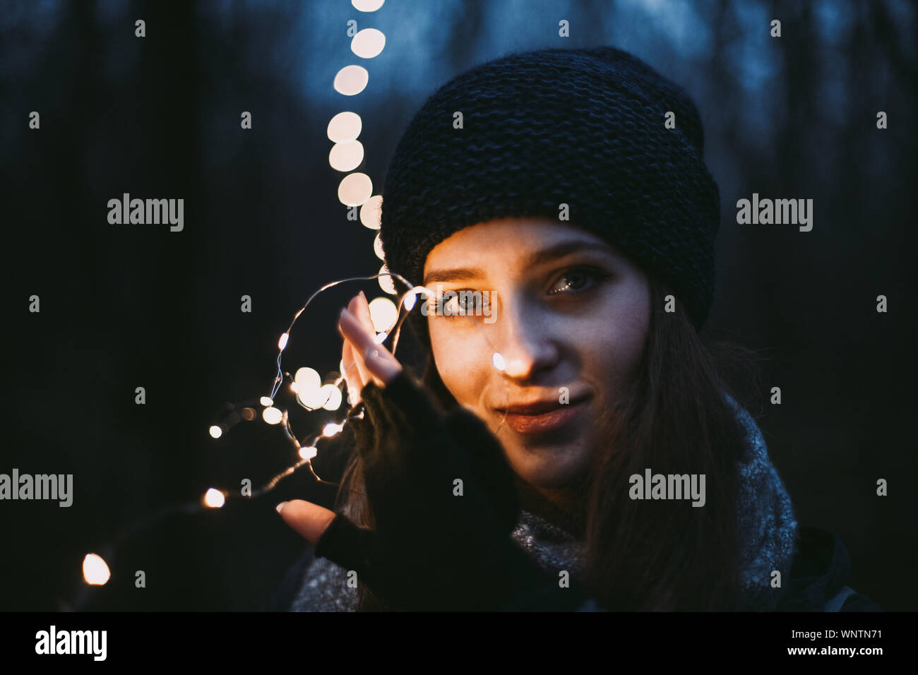 Close up portrait of beautiful young woman holding Christmas lights Stock Photo