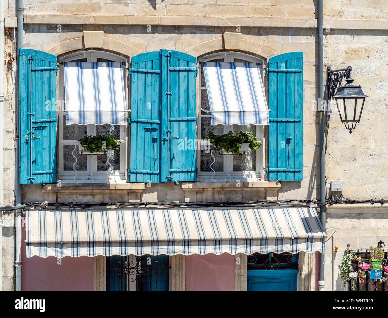 Windows framed by beautiful blue shutters and awnings. Stock Photo