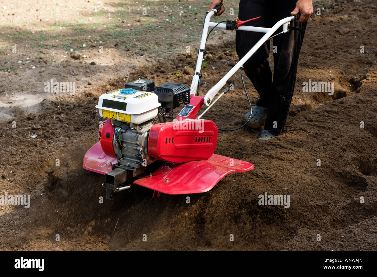 Man working in the garden with garden tiller machine. Garden tiller to work, close up Stock