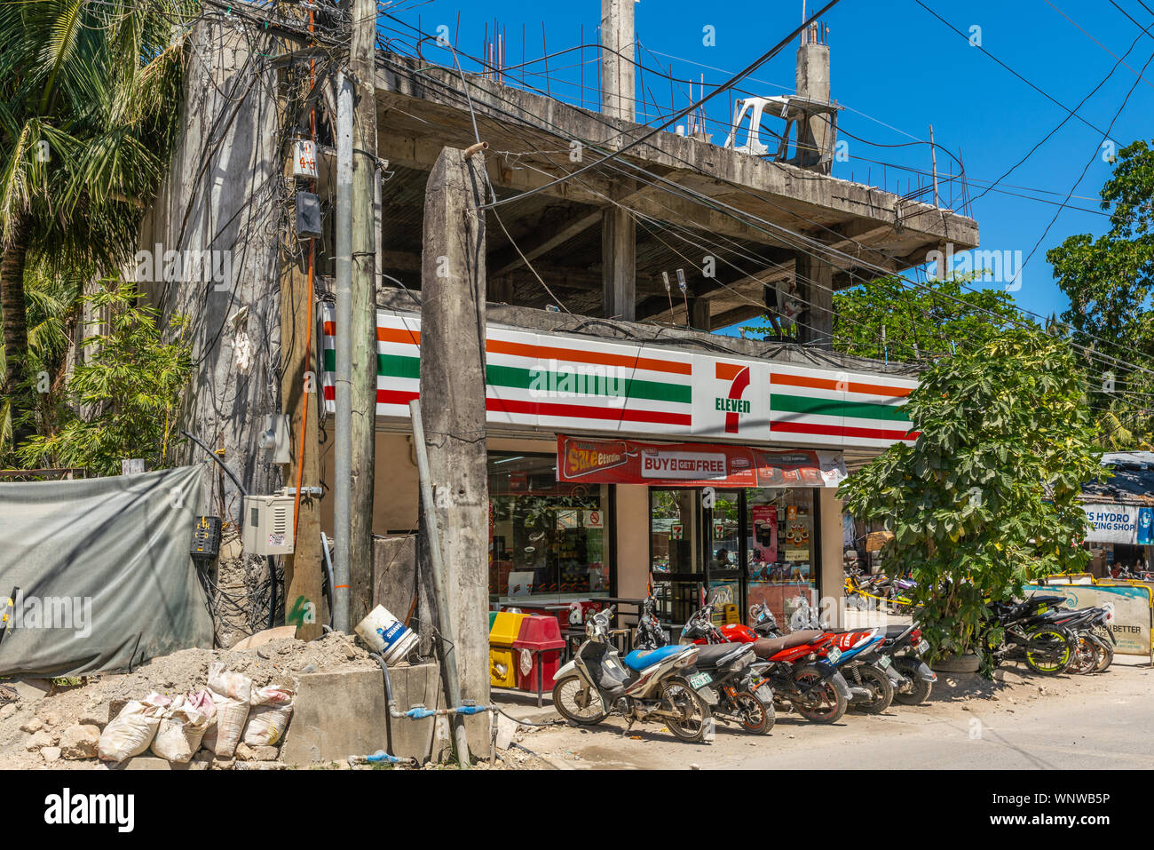 Manoc-Manoc, Boracay Island, Philippines - March 4, 2019: Near Cagban Jetty Port and ferry pier. Seven-Eleven store with line of motorbikes in front. Stock Photo