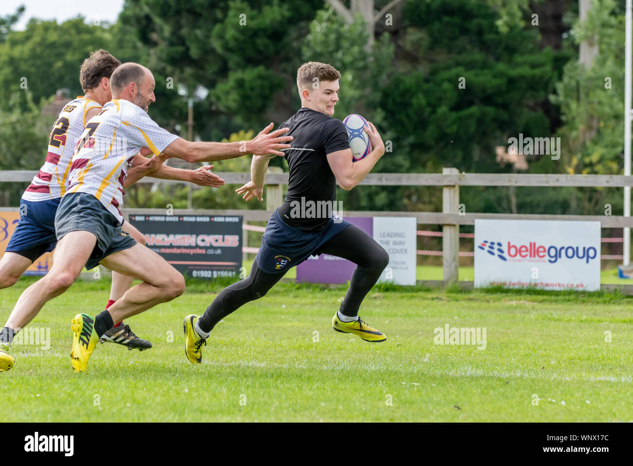 Amateur touch rugby , opposing players reach out to touch tackle player