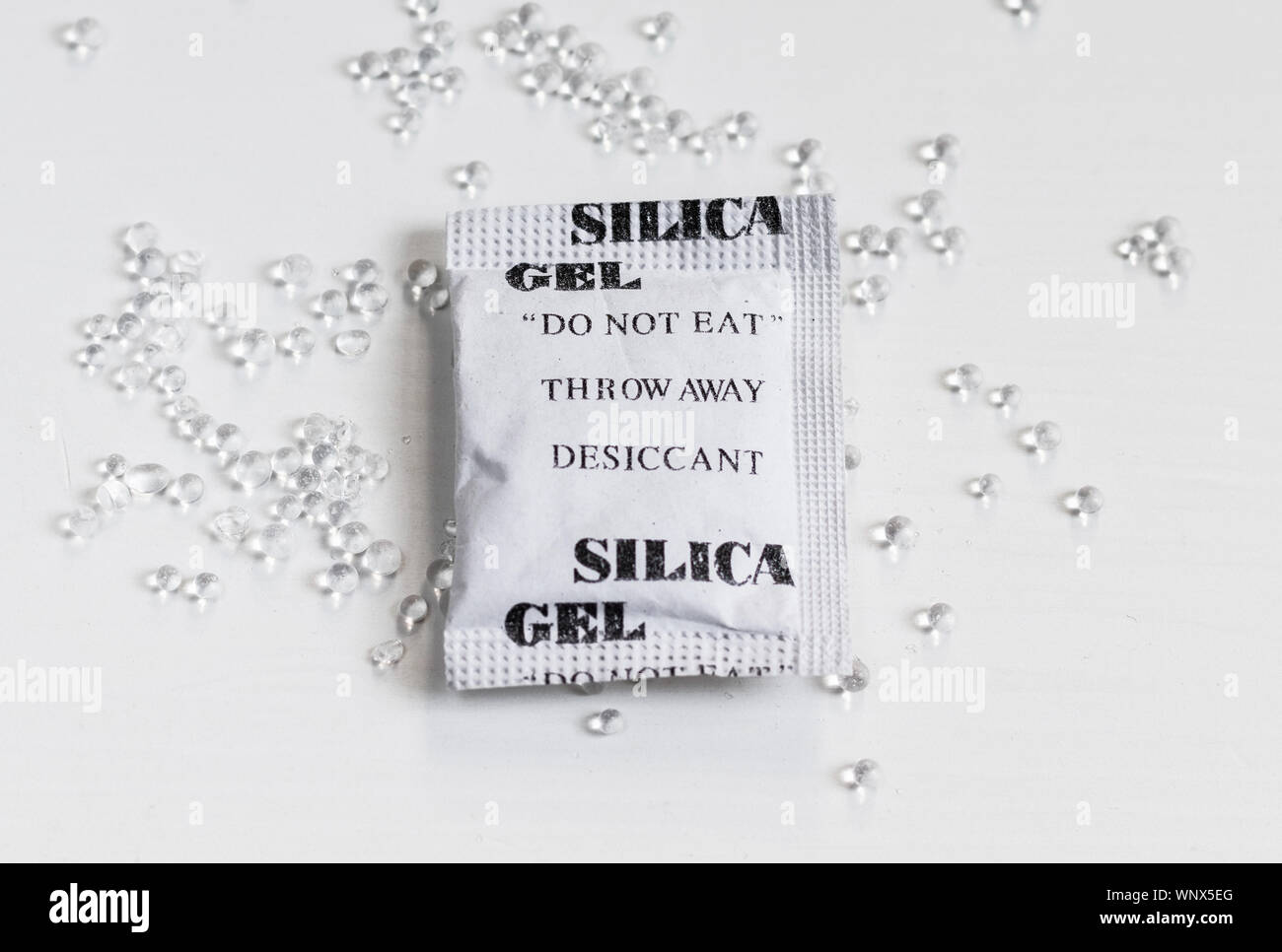 Packet of silica gel and beads on a white table surface Stock Photo