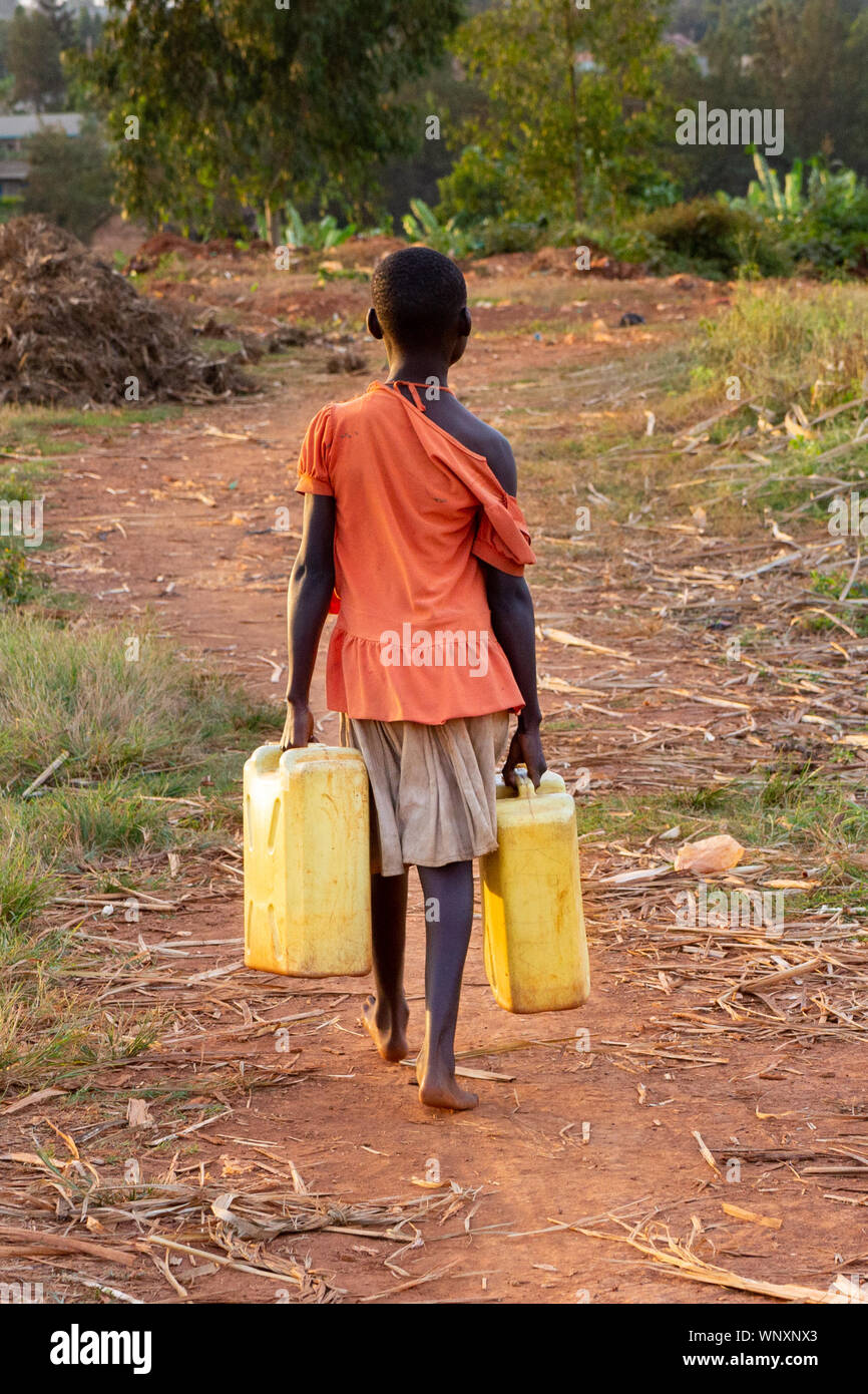 A young girl heading off carrying jerrycans full of water. Lugazi, Uganda. 13 June 2017. Stock Photo