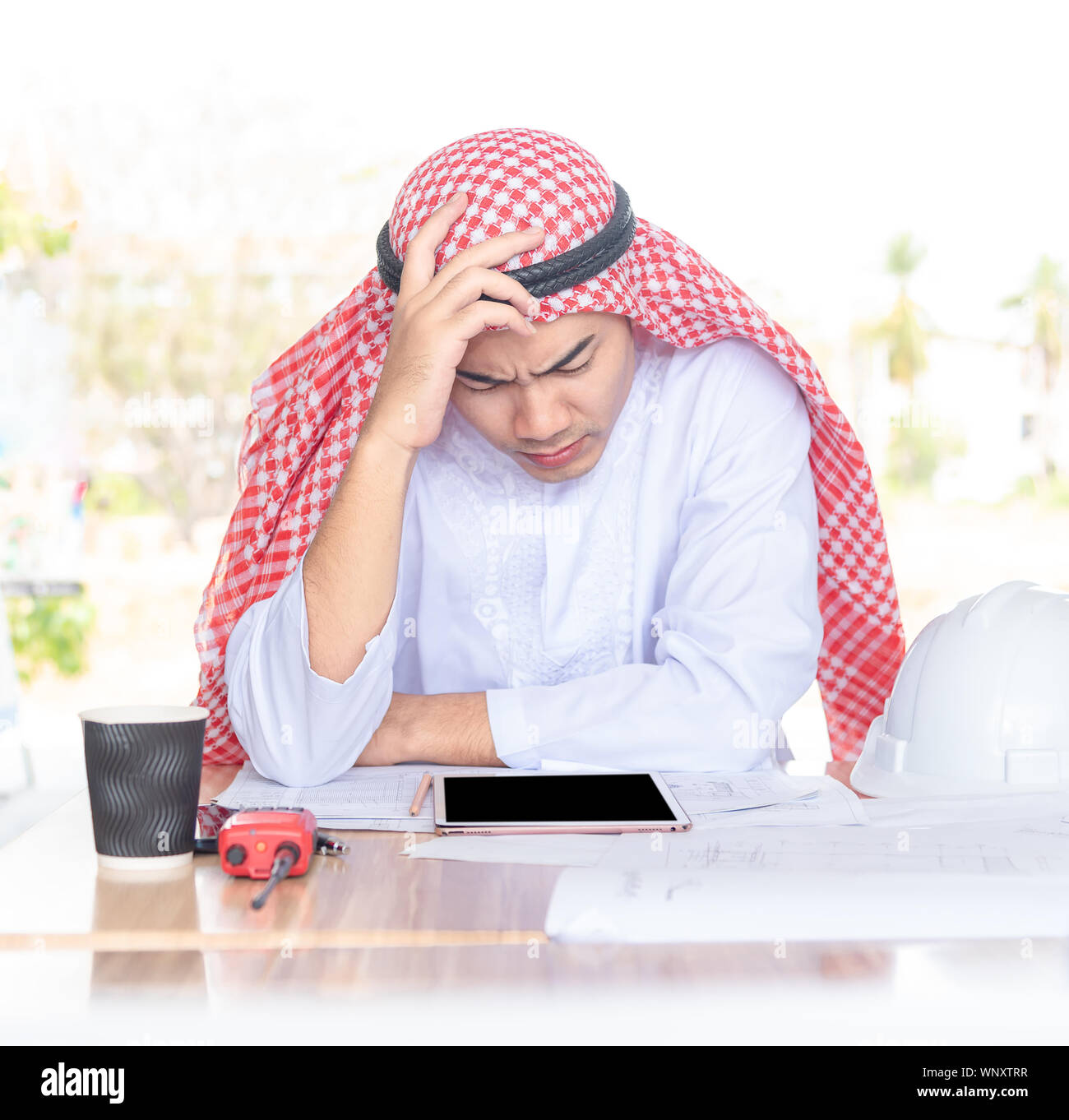 Seriously Arabian businessman working in modern startup office with tablet computer and document on table. Stock Photo