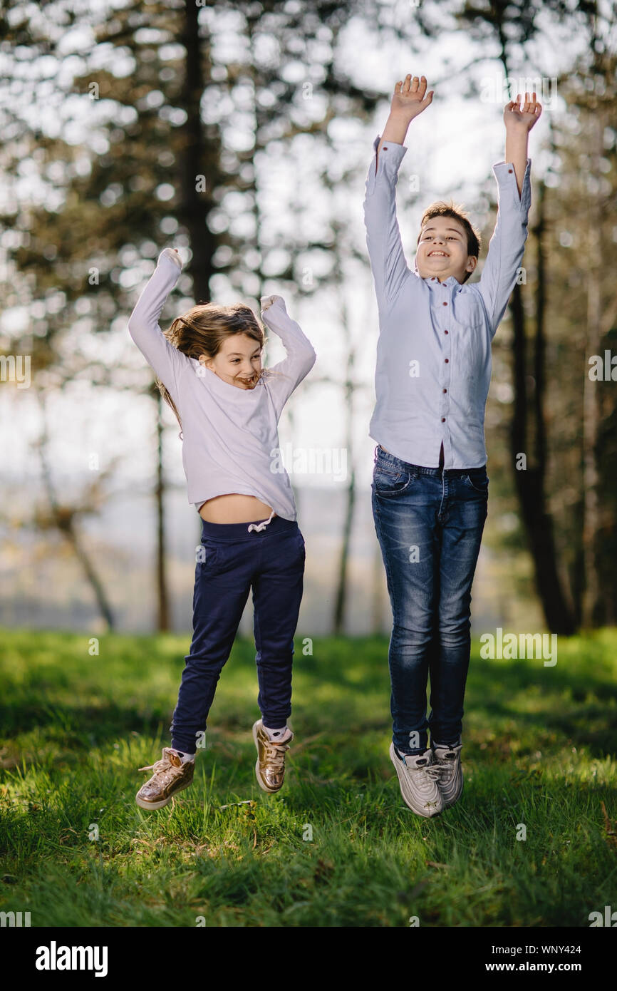Boy and Girl jumping and enjoy in nature. Happy kids playing in park. Stock Photo
