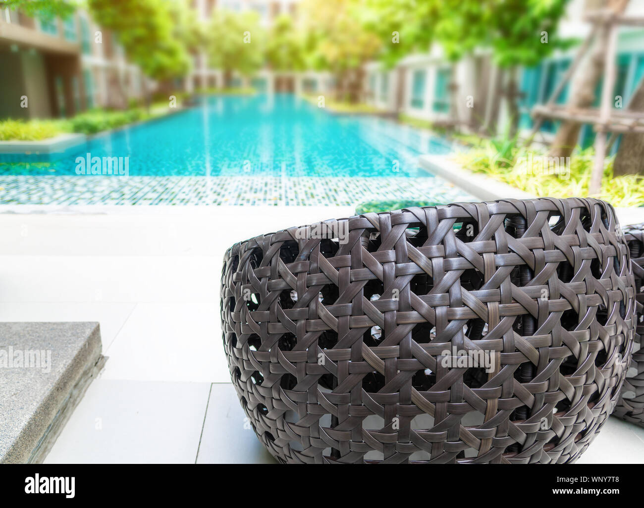The seat lounger ,brown rattan chairs beside swimming pool with background  is blurred of modern condominium or hotel or resort in summer day ,relax da  Stock Photo - Alamy